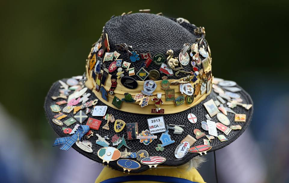 Un accanito appassionato di golf, spettatore alla Ryder Cup, indossa un curioso cappello ricoperto di spille-gadget di vari eventi golfistici (Ap)